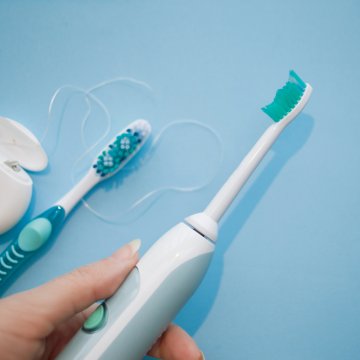 electric toothbrush beside a manual toothbrush